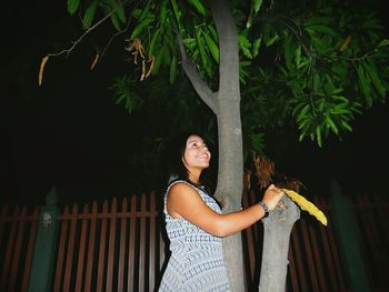 Portrait of a smiling young woman standing against trees