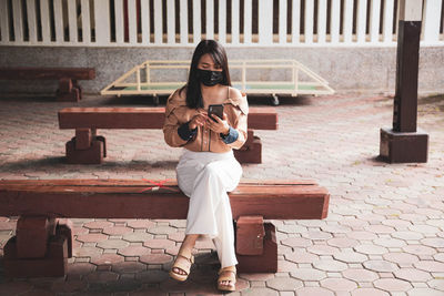 Full length portrait of young woman using mobile phone