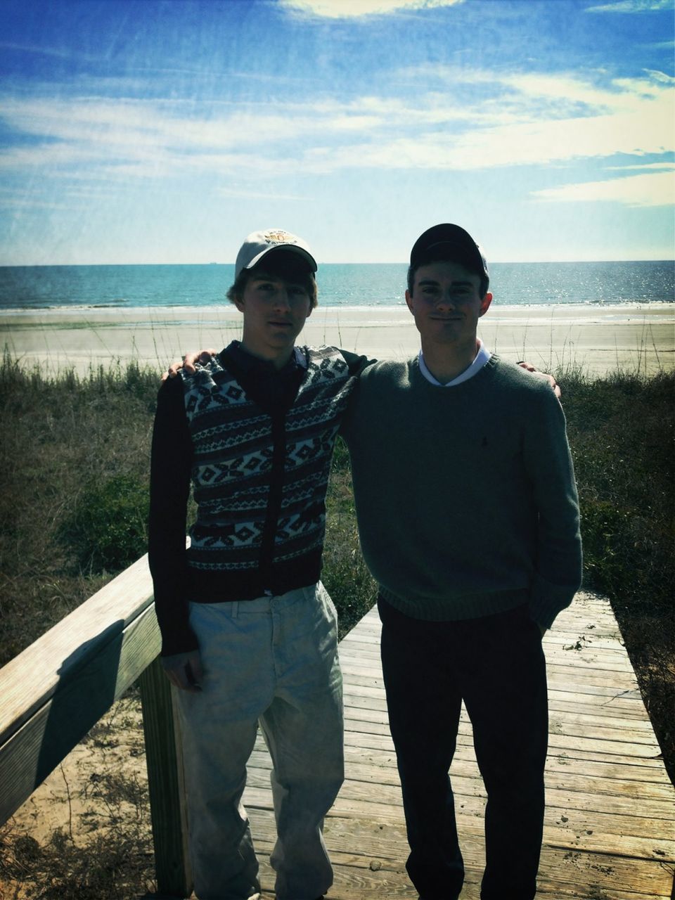 sea, sky, lifestyles, casual clothing, water, beach, standing, leisure activity, horizon over water, person, railing, young men, shore, togetherness, sitting, full length, three quarter length