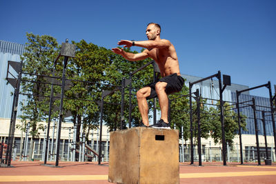 Low angle view of young man standing against trees