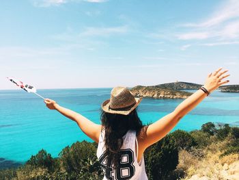 Rear view of woman standing by sea against sky