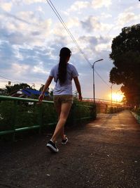 Woman with arms raised at sunset