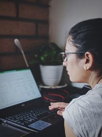 Woman using laptop while sitting on table during pandemic. working online