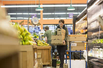 Female worker carrying boxes while working at supermarket