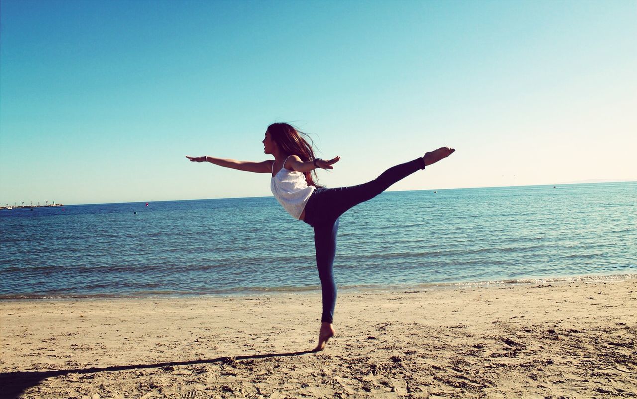 sea, full length, leisure activity, water, lifestyles, beach, clear sky, horizon over water, shore, arms outstretched, arms raised, vacations, standing, enjoyment, copy space, sky, carefree, fun