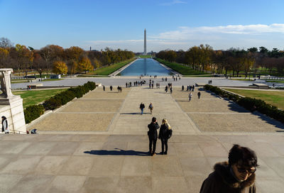 People at washington monument against sky