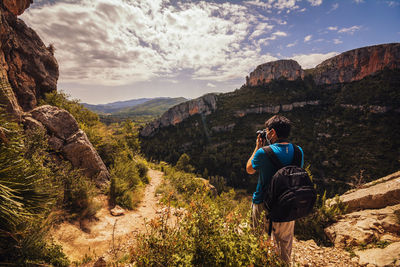 Man with backpack taking a photo in a mountain landscape