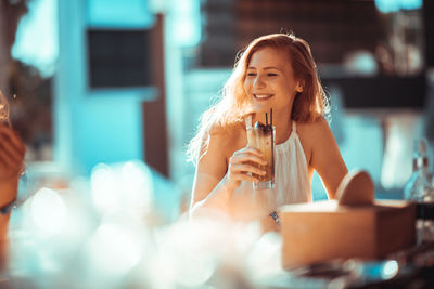 Close-up of a smiling young woman drinking drink
