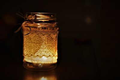 Close-up of illuminated lamp on table against black background