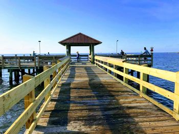 Wooden pier leading to sea against clear sky