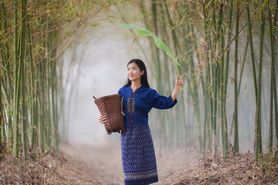 Beautiful woman with basket standing by tree