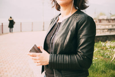 Midsection of woman listening to music with mobile phone