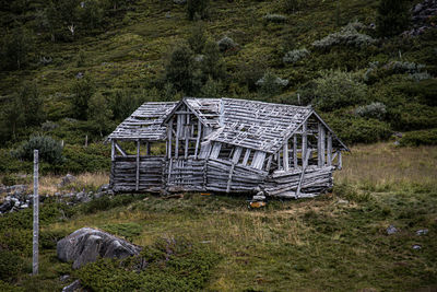 Abandoned house on field against trees