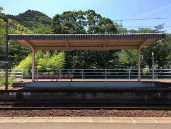 Railroad station platform by trees against sky