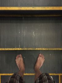 Low section of man standing on escalator