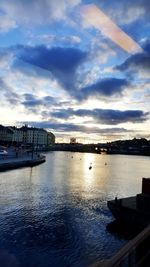 Boats in harbor against cloudy sky