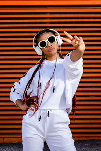 Young african american woman with braided hair wearing urban sportswear with headphones and sunglass