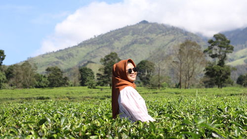 Young woman wearing sunglasses in farm against sky