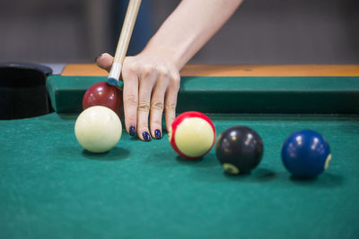 Cropped hand of woman playing pool on table