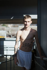 Portrait of shirtless young man standing indoors