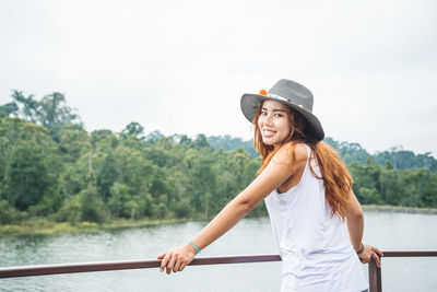 Portrait of smiling young woman standing by river