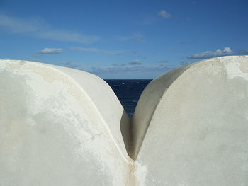 Wall by sea against sky