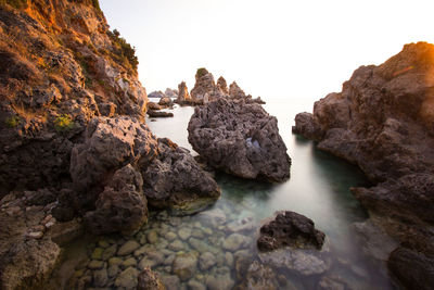 Rocks on sea shore against clear sky