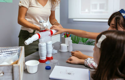 Student putting a piece in recycled toy robot made with plastic packages