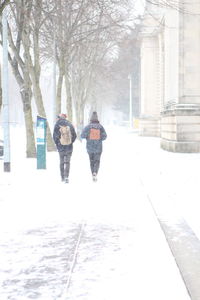 Rear view of women walking on snow covered street