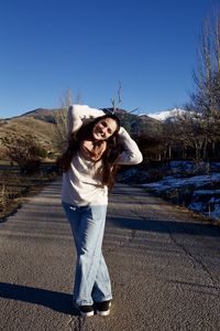 Portrait of a smiling young woman standing against clear sky