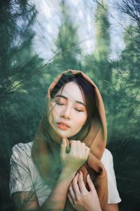 Young woman with eyes closed against trees