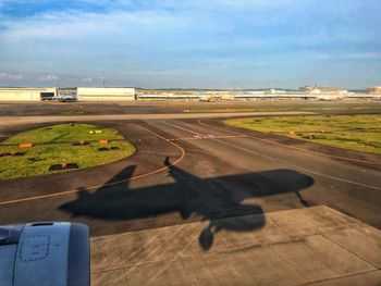 Airplane on airport runway against sky