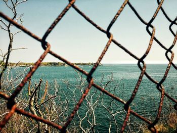 View of sea seen through chainlink fence