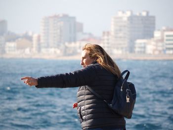 Woman with umbrella against sea in city