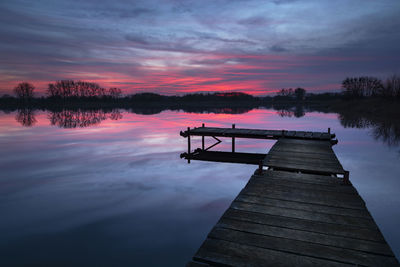 Sunset with dramatic clouds, lake and wooden jetty