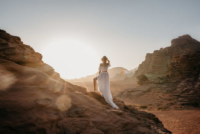 Woman standing on rock formation against clear sky