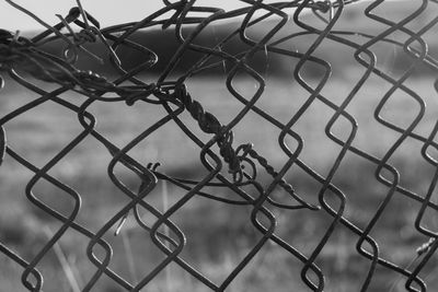 Close-up of barbed wire fence against sky