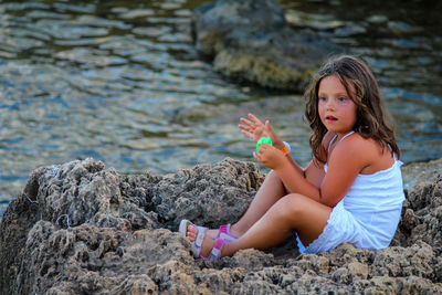 Girl sitting on rock by water