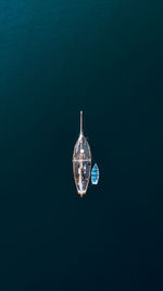 Aerial view above a luxury sailing yacht sailing towards the light on the ocean in a concept of hope