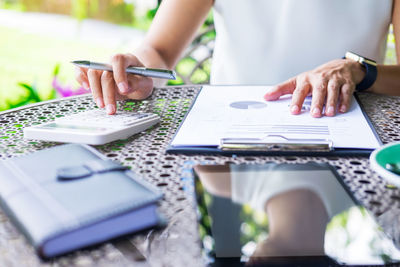 Midsection of businesswoman working on table at office