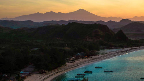 Aerial view of sea by mountains during sunset