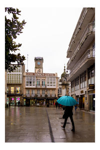 Rear view of man walking on wet street in city