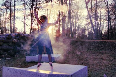 Ballet dancer with distress flare dancing in forest during sunset