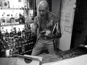 Shirtless mature man screaming while looking at digital tablet in store