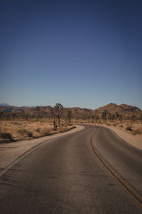 Road by desert against clear blue sky