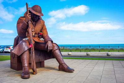 Man looking away while sitting on sea against sky