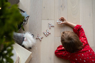 Top view of boy in an elf costume holding ceramic letters xmas
