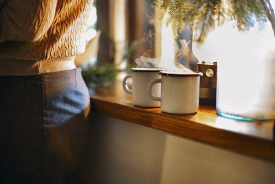 Rear view of woman holding coffee on table