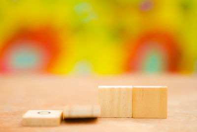 Close-up of wooden blocks on table against multi colored background