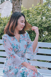 Young woman standing against plants